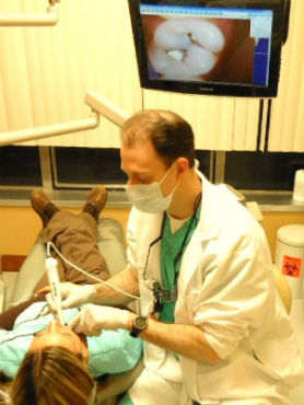 Dr. Calcaterra with an intraoral camera taking pictures of her tooth to show her the cavities